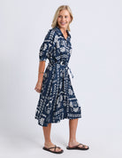 Woman wearing a navy blue dress with white patterns on a white background