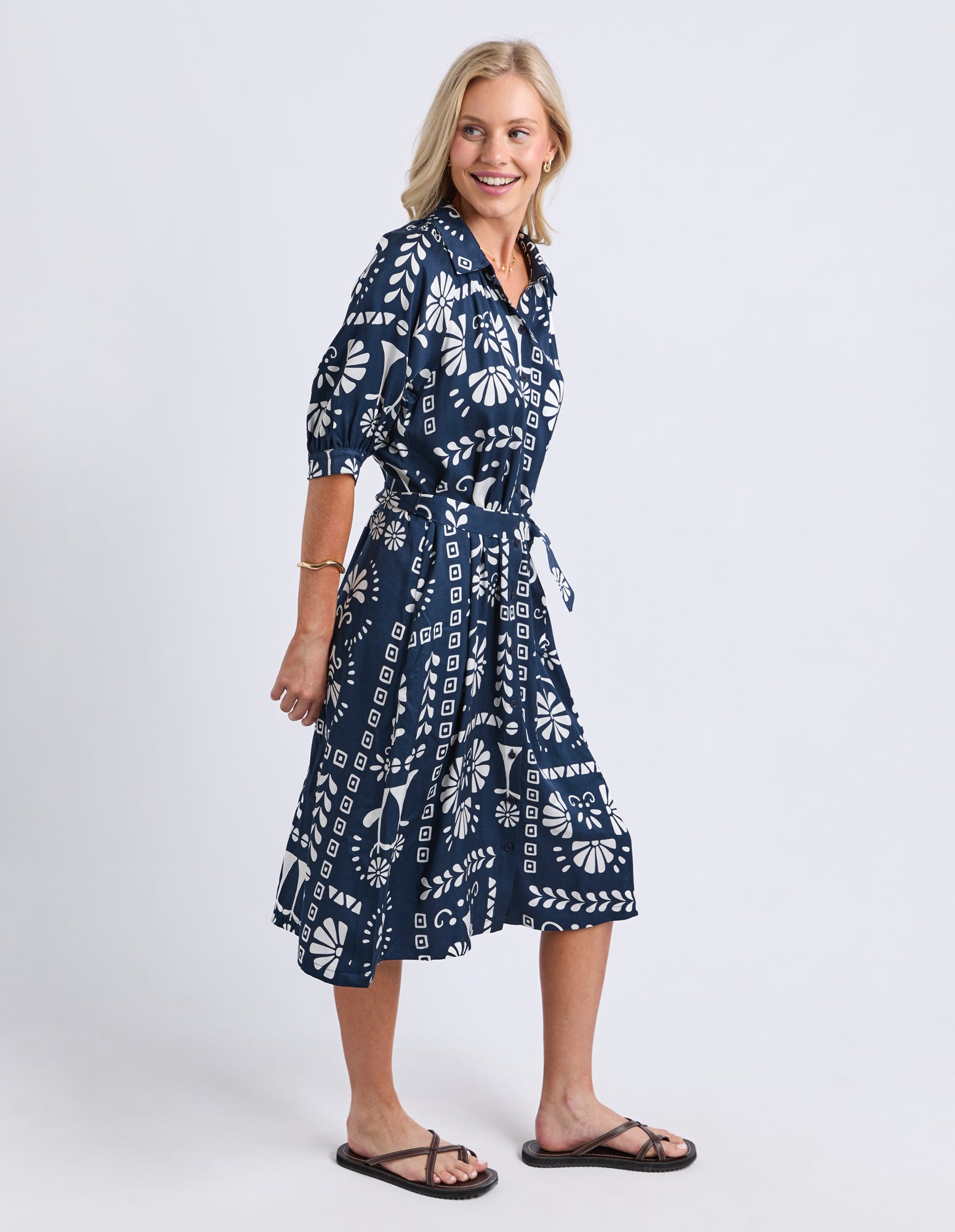 Woman wearing a navy blue dress with white patterns on a white background