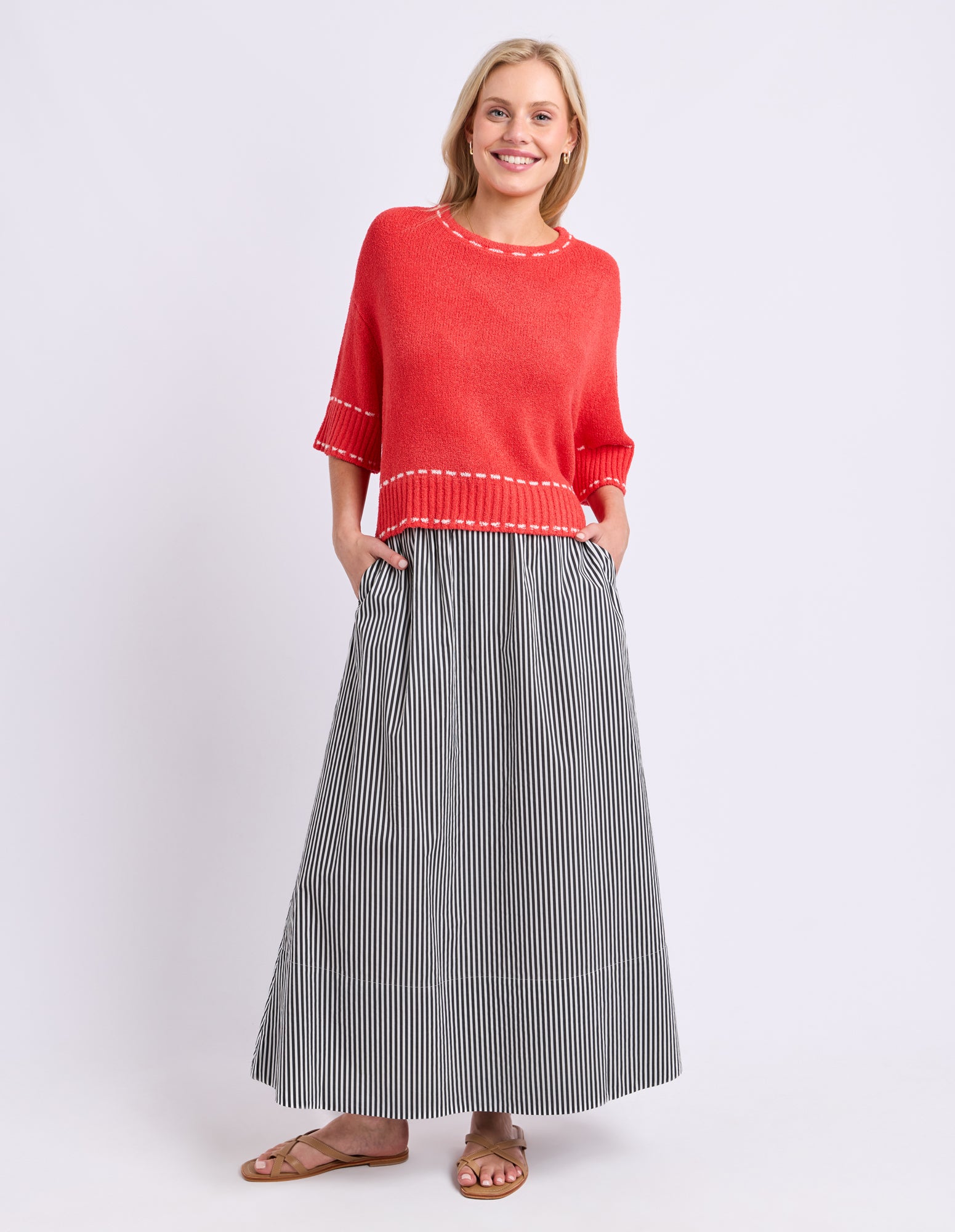 Woman wearing a red sweater and striped skirt on a white background