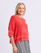 Woman wearing a red sweater with white trim on a light gray background