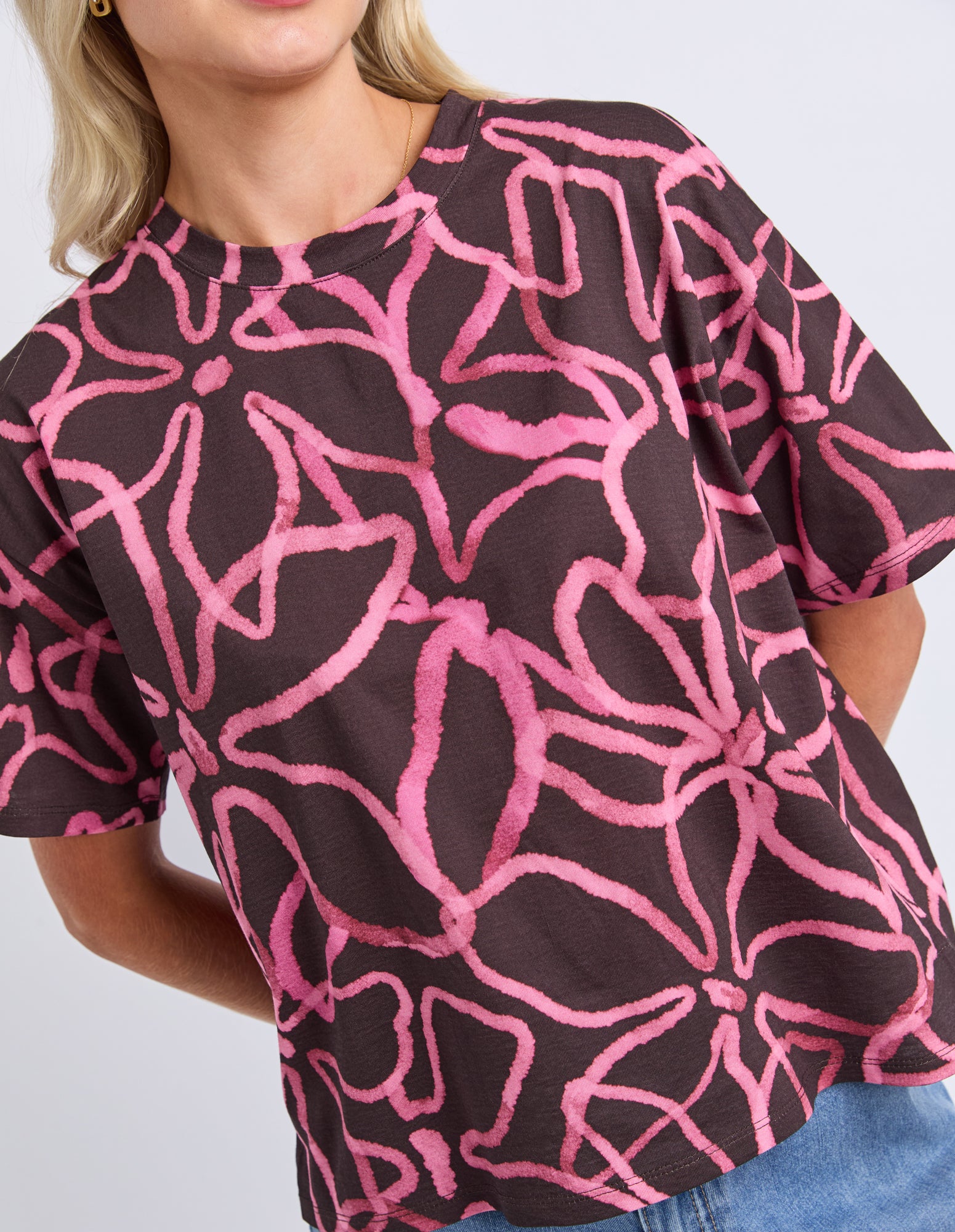Person wearing a brown top with pink abstract pattern on a white background