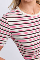 A close-up of a woman wearing a short-sleeve ribbed top with horizontal stripes in pink, black, and white, paired with a delicate gold necklace.