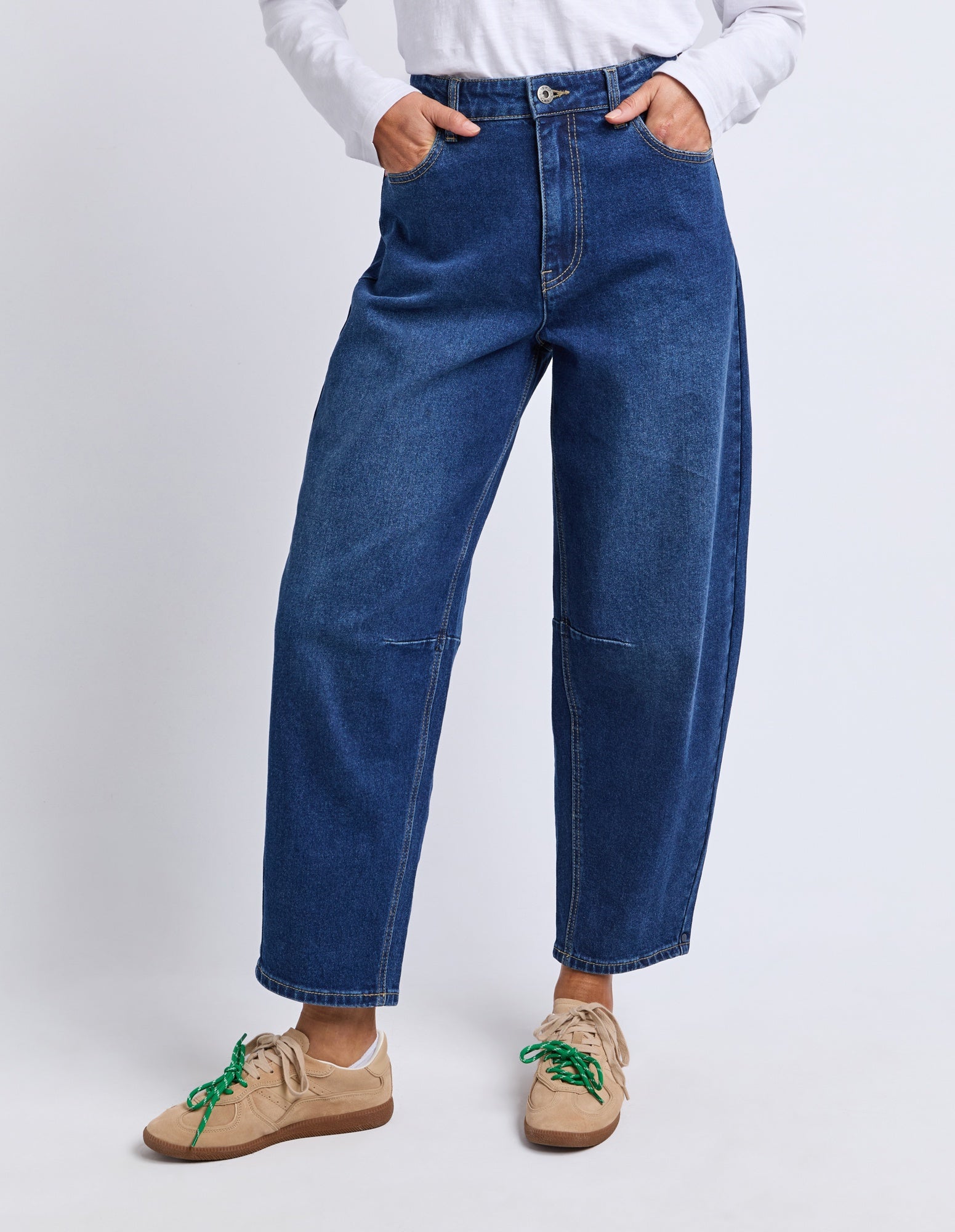 Person wearing blue jeans and beige shoes on a white background