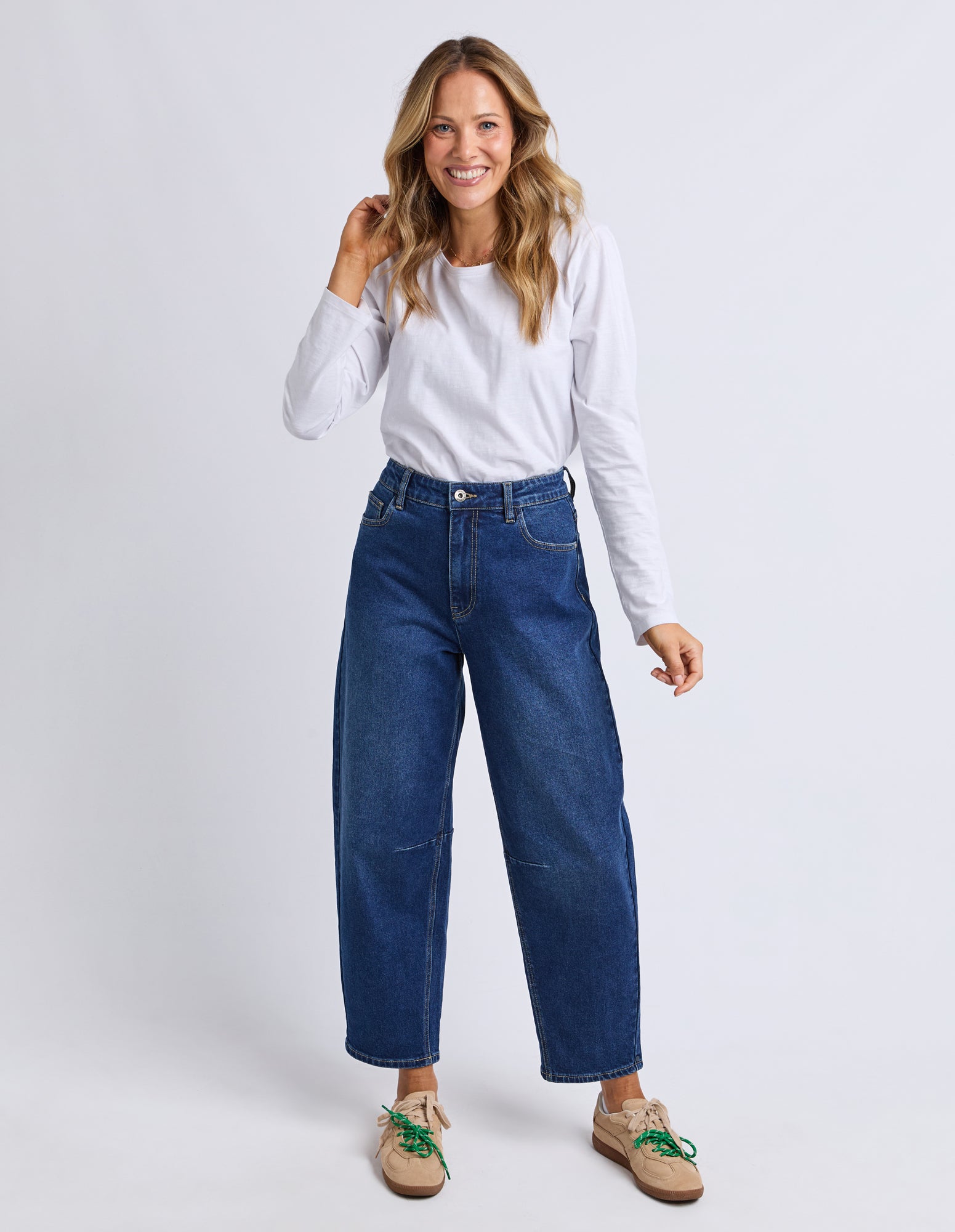 Woman wearing blue jeans and a white shirt on a plain background