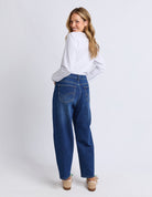 Woman wearing blue jeans and a white shirt on a plain background