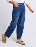 Person wearing blue jeans and beige shoes on a white background