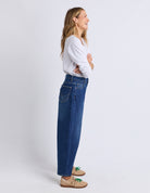 Woman wearing blue jeans and a white shirt on a light gray background