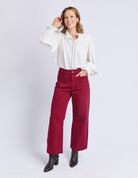 Woman wearing a white blouse and red pants on a white background