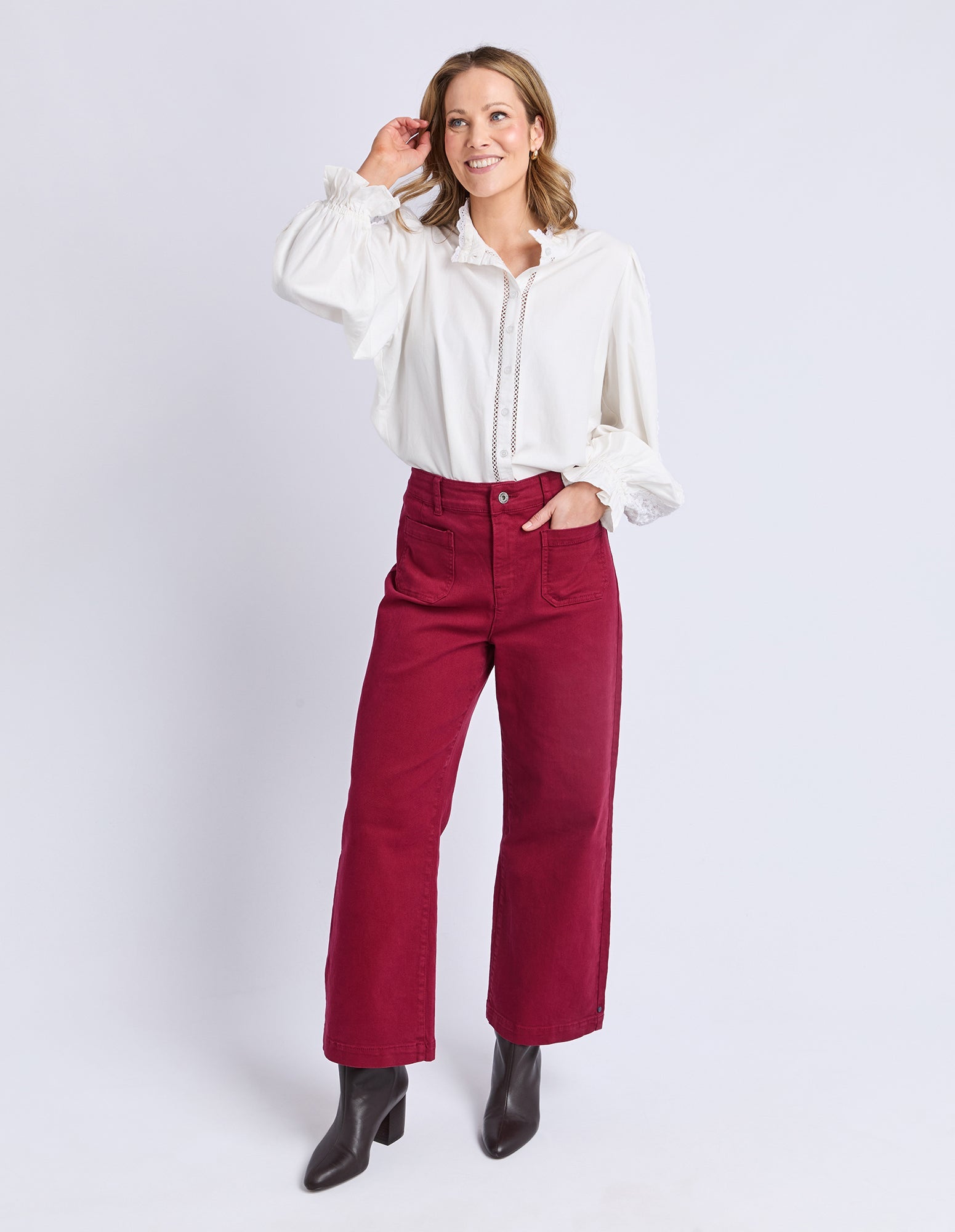 Woman wearing a white blouse and red pants on a white background