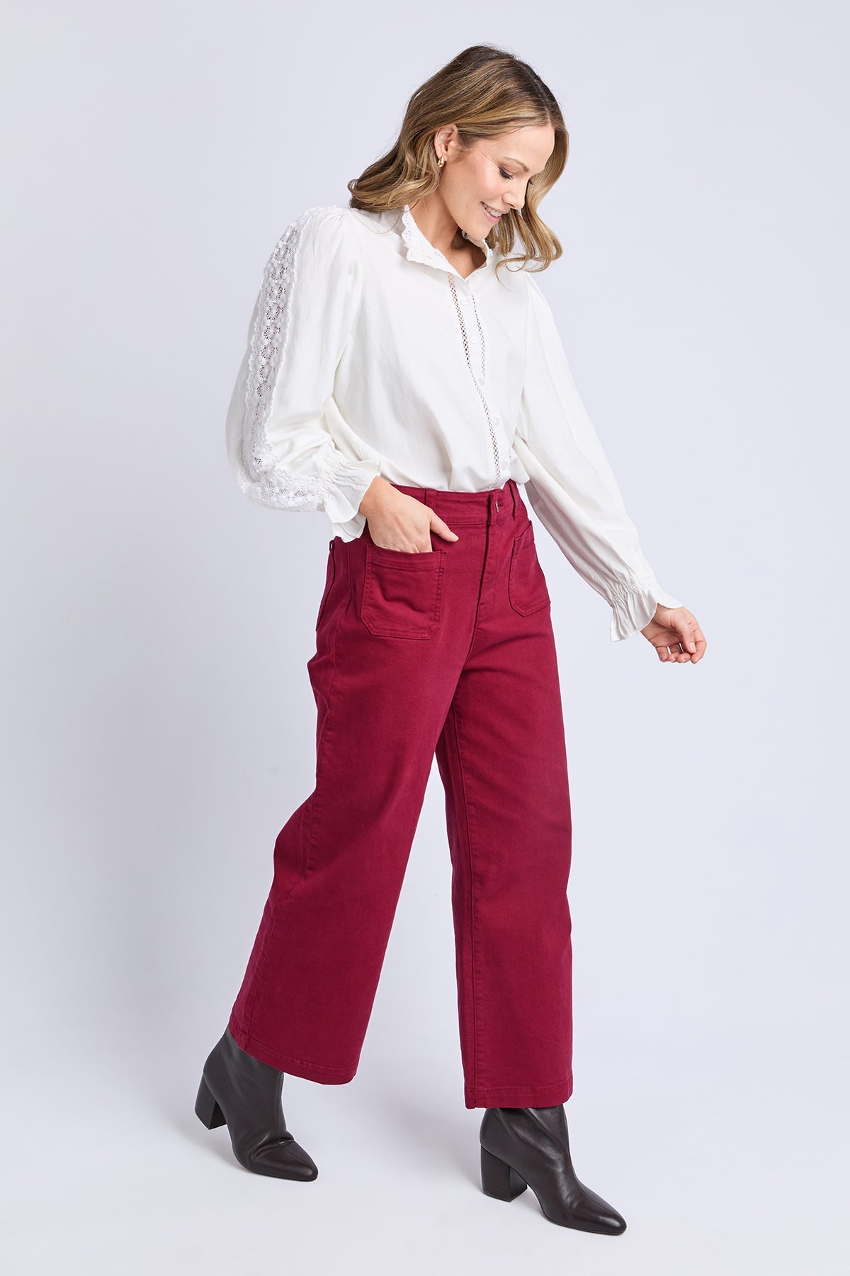 Woman wearing a white blouse and red pants on a white background