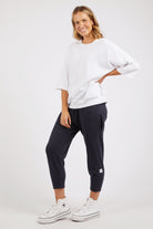 Woman wearing a white oversized shirt and navy jogger pants on a white background