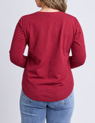 Person wearing a red long-sleeve shirt and blue jeans on a light gray background