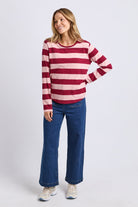 Woman wearing a red and white striped sweater and blue jeans on a white background