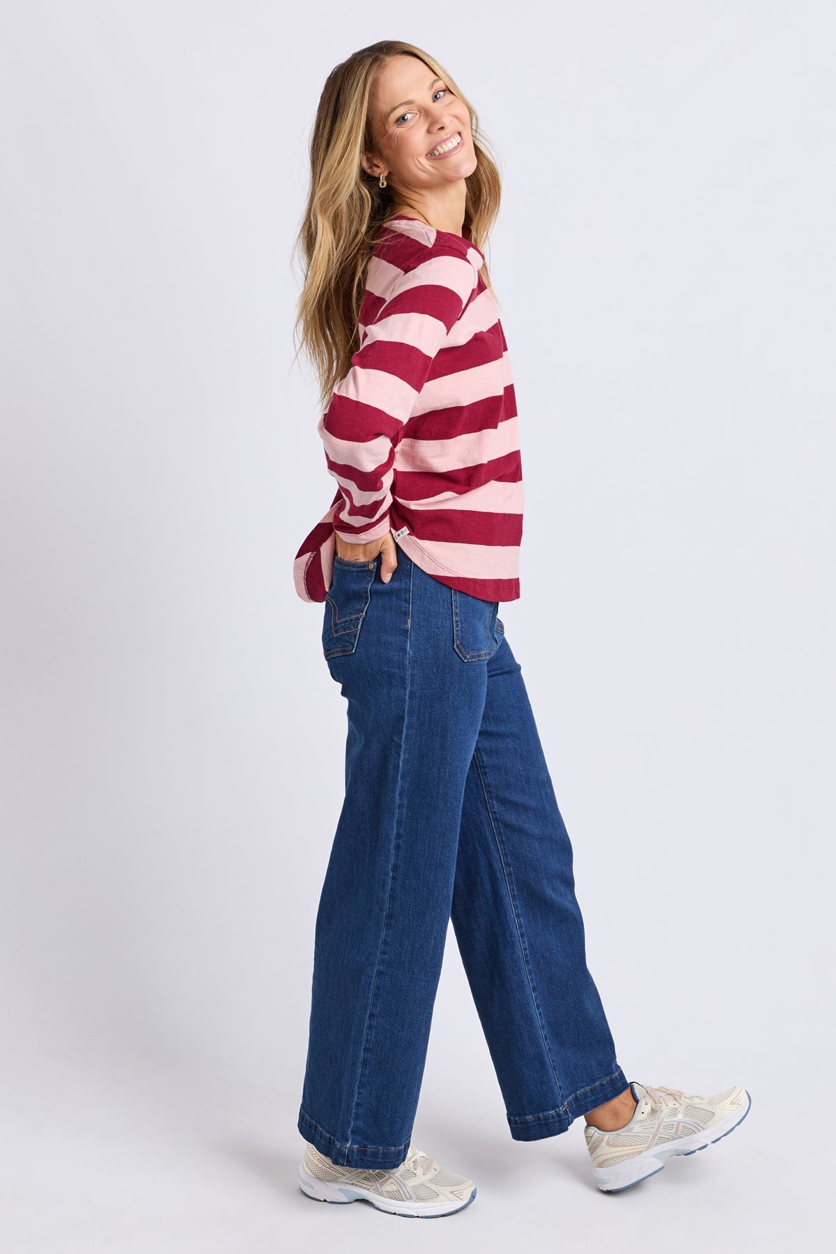 Woman wearing a red and white striped sweater and blue jeans on a white background