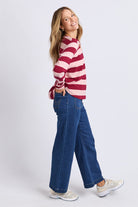 Woman wearing a red and white striped sweater and blue jeans on a white background