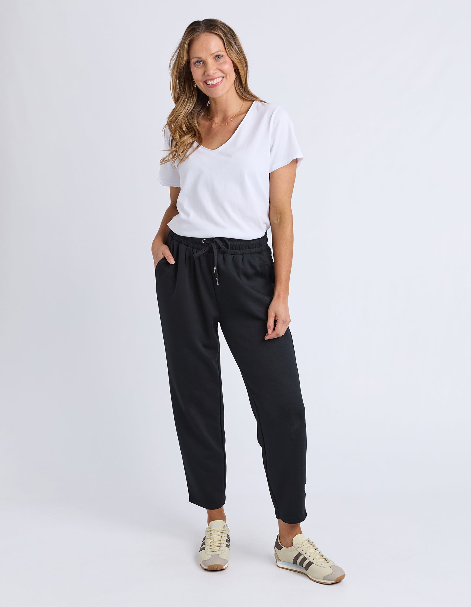 Woman wearing a white t-shirt and black pants on a white background