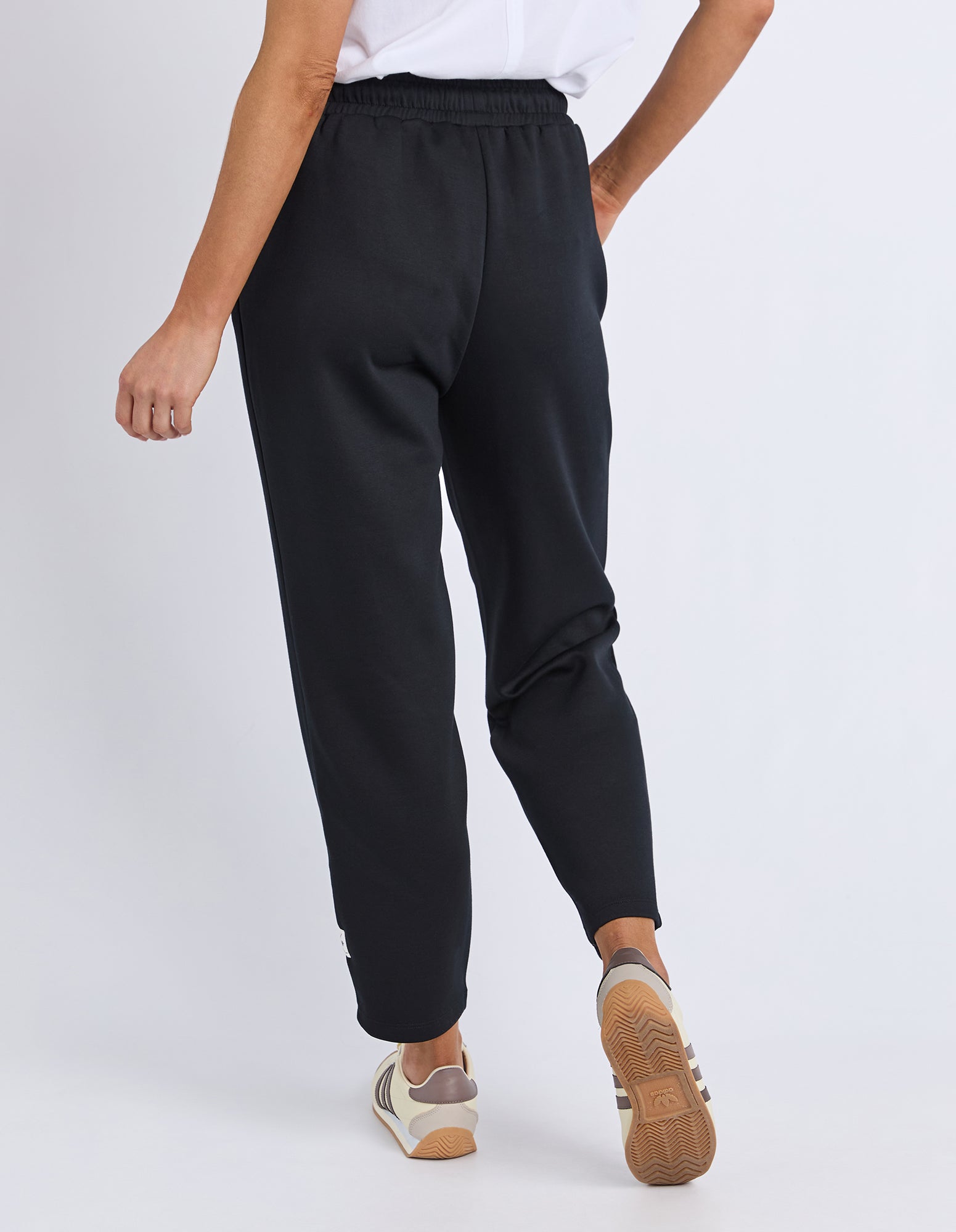 Person wearing black jogger pants on a white background