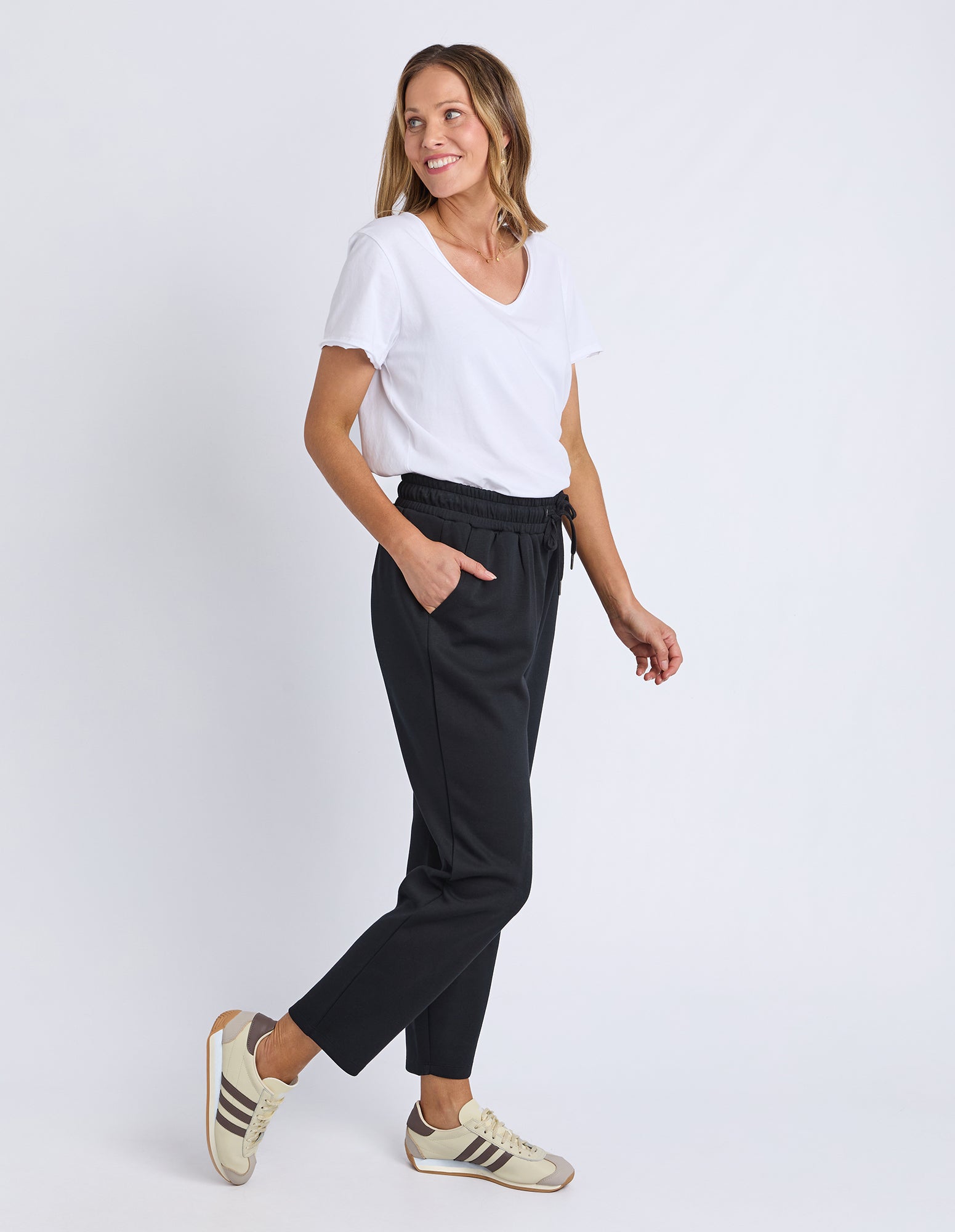 Woman wearing a white t-shirt and black pants on a white background