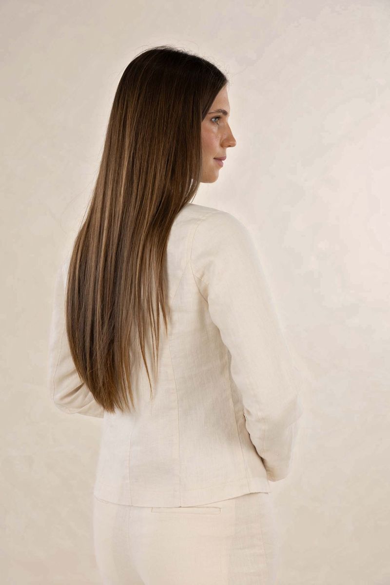 Woman with long hair wearing a white outfit against a plain background