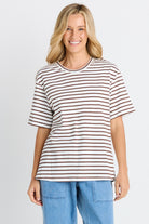 Woman wearing a striped shirt and blue jeans on a plain background