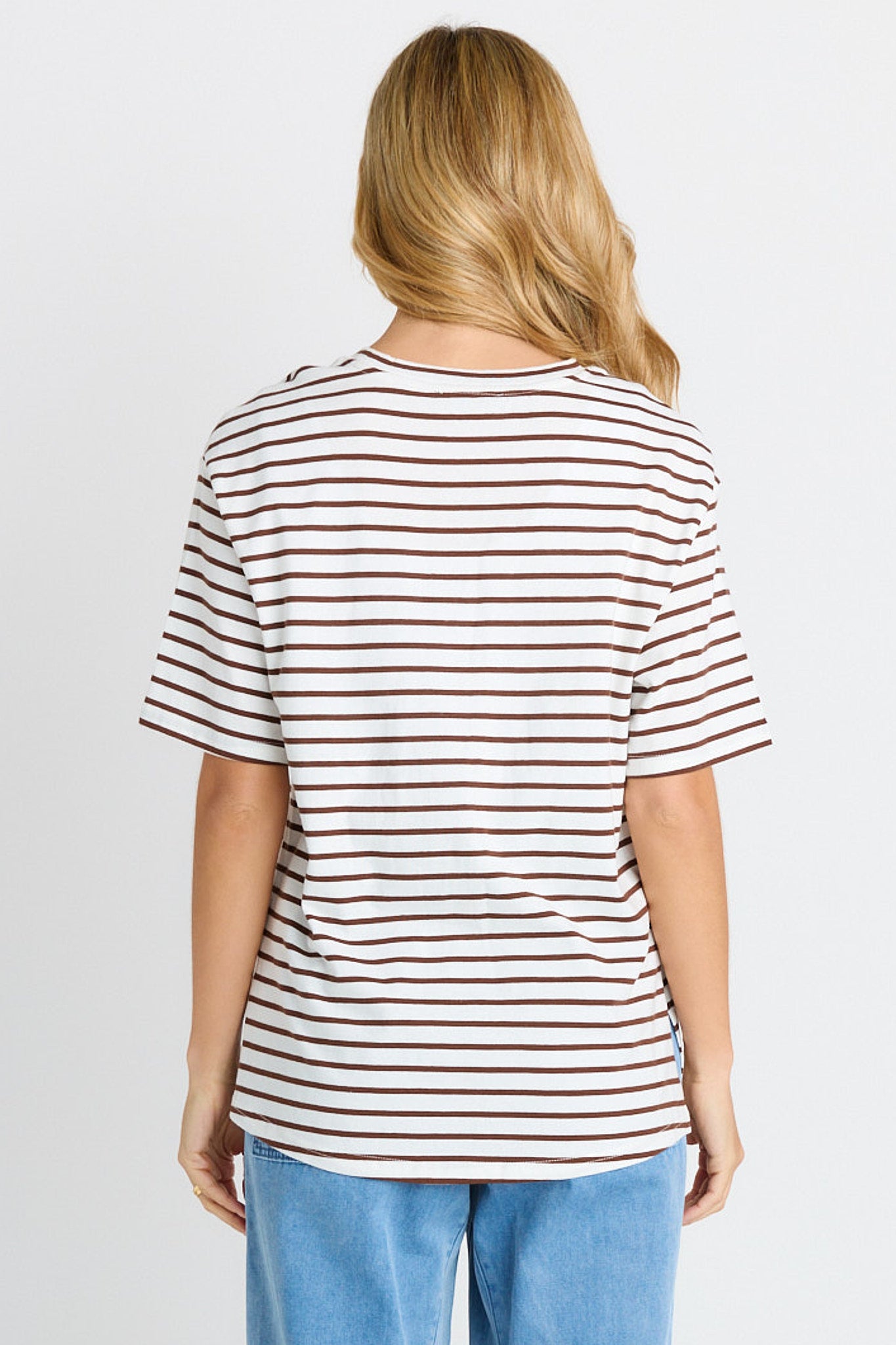 Person wearing a striped t-shirt and blue jeans on a plain background