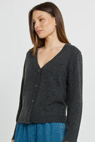 Woman wearing a dark gray cardigan over a blue dress on a light gray background
