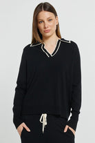 Woman wearing a black outfit with white trim on a light gray background