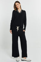 Woman wearing a black outfit with white accents on a white background