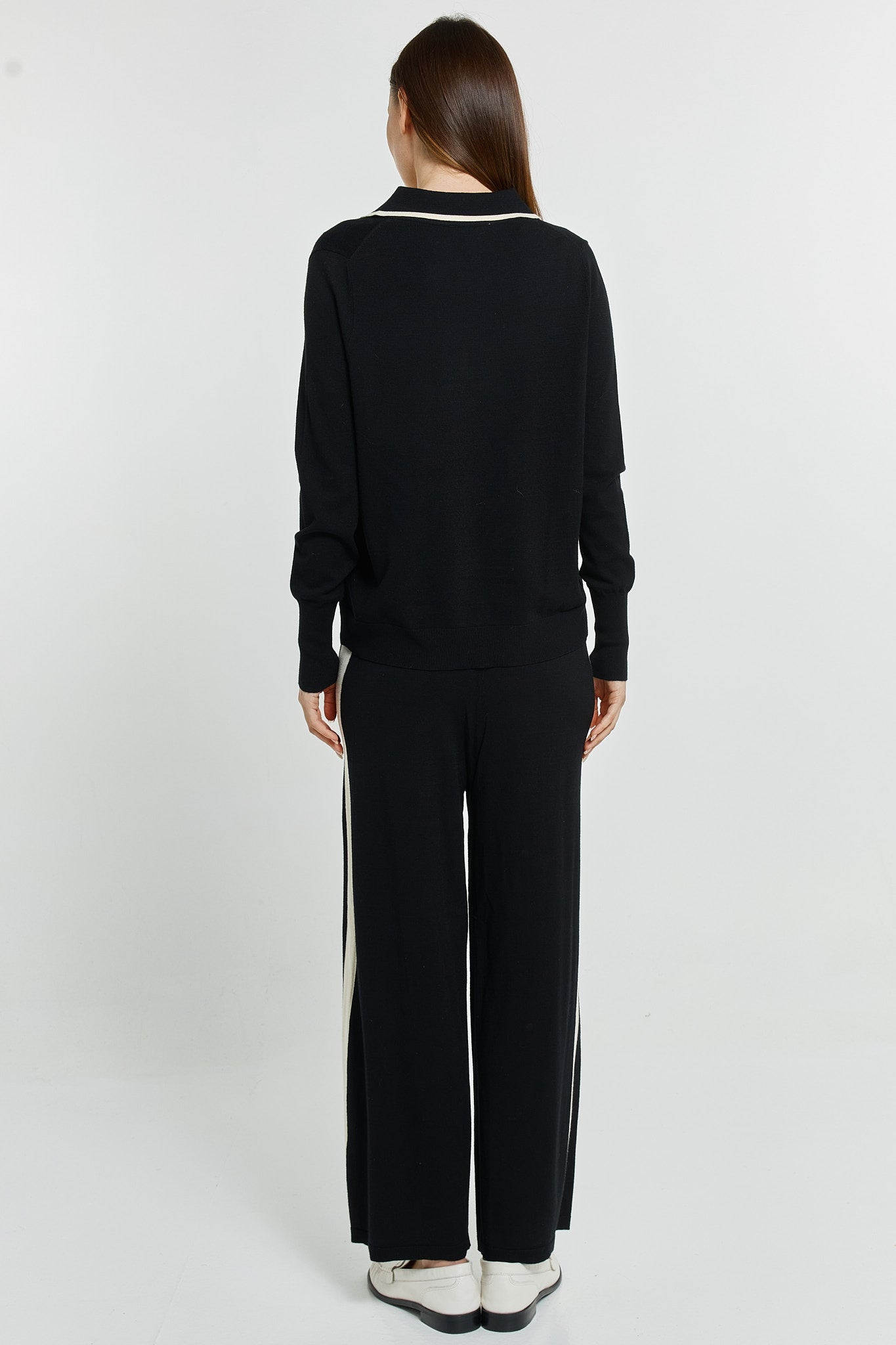 Person wearing a black outfit with white stripes on a white background
