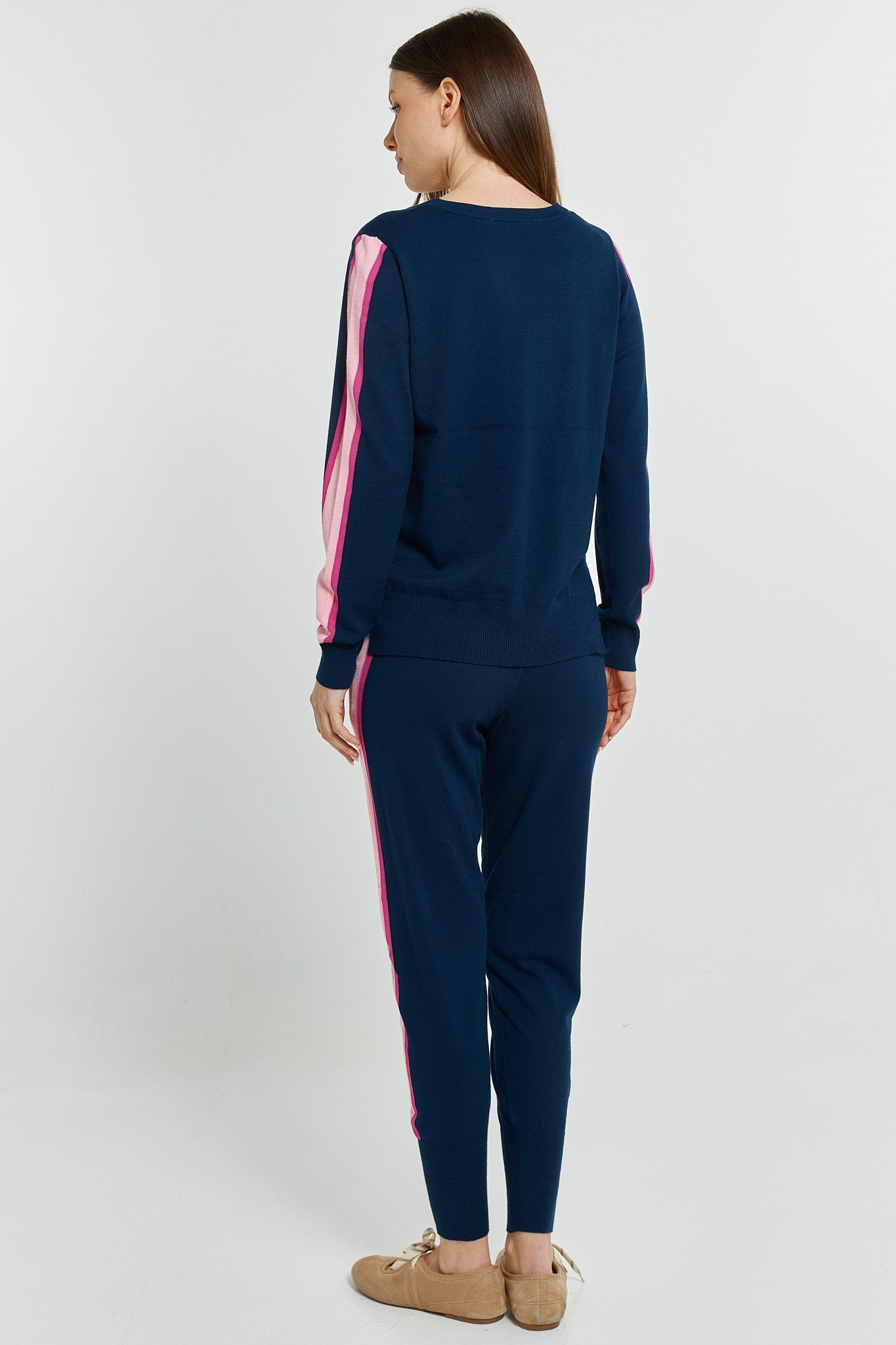 Person wearing a navy tracksuit with pink stripes on a white background