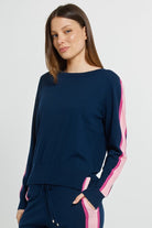 Woman wearing a navy blue outfit with pink accents on a plain background