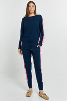 Woman wearing a navy tracksuit with pink stripes on a white background