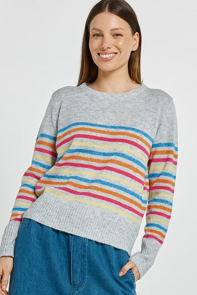 Woman wearing a gray sweater with colorful stripes on a white background
