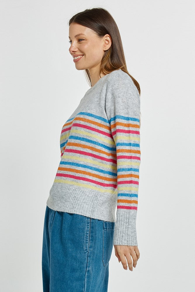 Woman wearing a gray sweater with colorful stripes on a white background