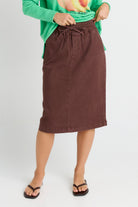 Person wearing a brown skirt and green top on a white background