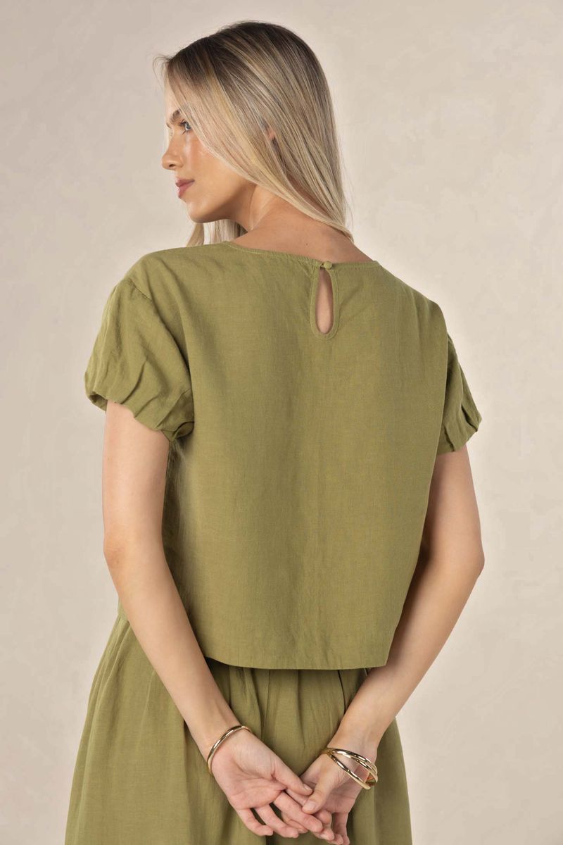 Woman wearing an olive green dress with a plain background