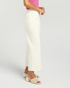 A model is shown from the waist down wearing a pair of off-white cropped wide-leg trousers, paired with a pink knit top and beige block-heel mule sandals, against a light gray studio background.