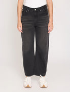 Person wearing black wide-leg jeans on a plain background