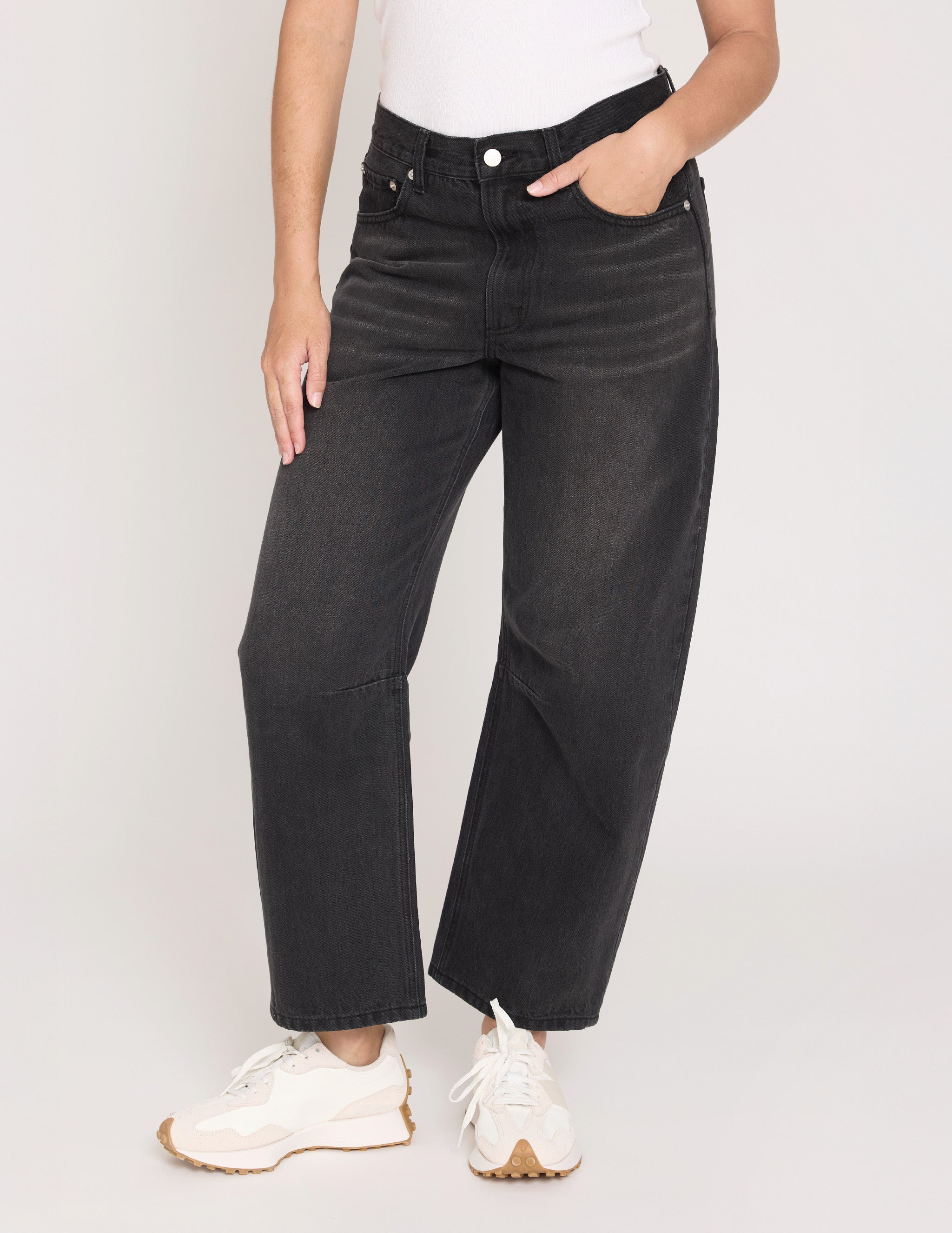 Person wearing black wide-leg jeans on a plain background