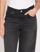 Person wearing black jeans with a plain background