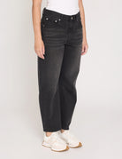 Person wearing black jeans and white sneakers on a plain background