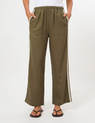 A person wearing olive green wide-leg pants with white side stripes, shown from the waist down against a plain light background.