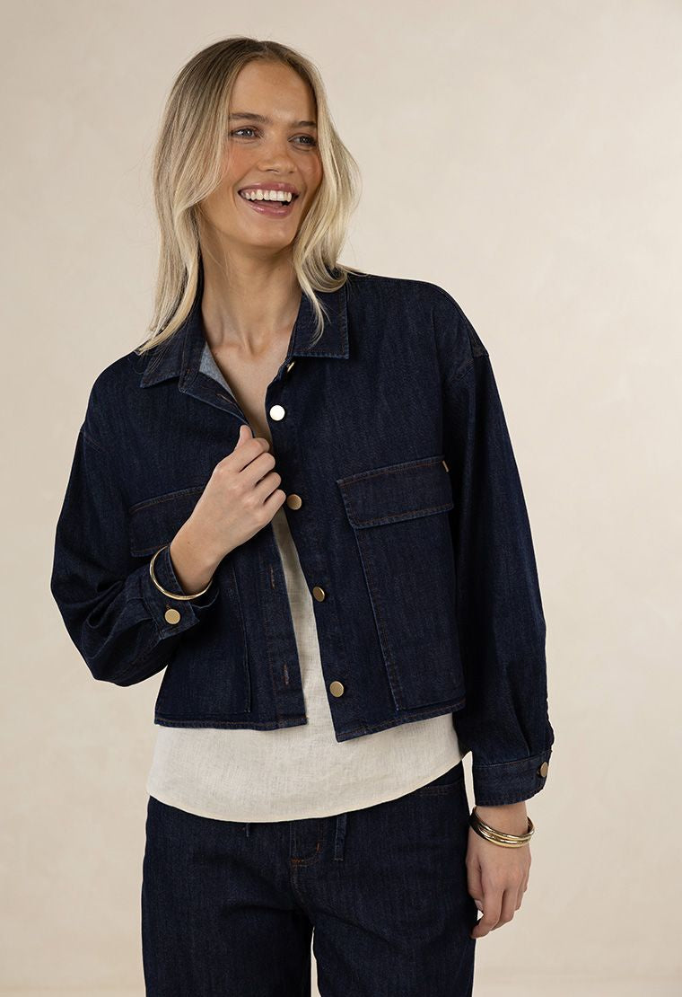 Woman wearing a dark denim jacket on a beige background