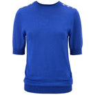 A royal blue short-sleeve knit sweater with decorative gold-tone metal buttons on the shoulders, shown against a plain white background.