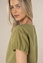 Woman wearing a green blouse against a beige background
