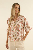 Women wearing a beige coloured floral blouse in front aof a neutral background