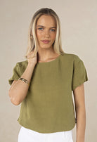 Woman wearing a green top against a beige background