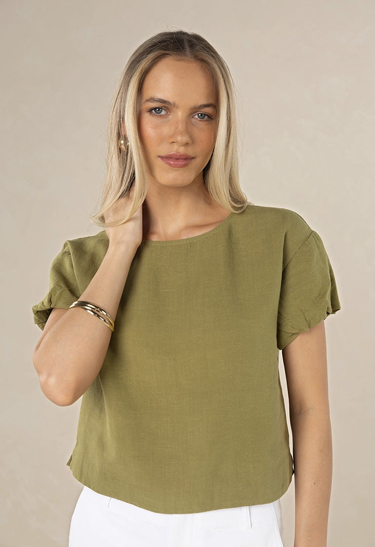 Woman wearing a green top against a beige background