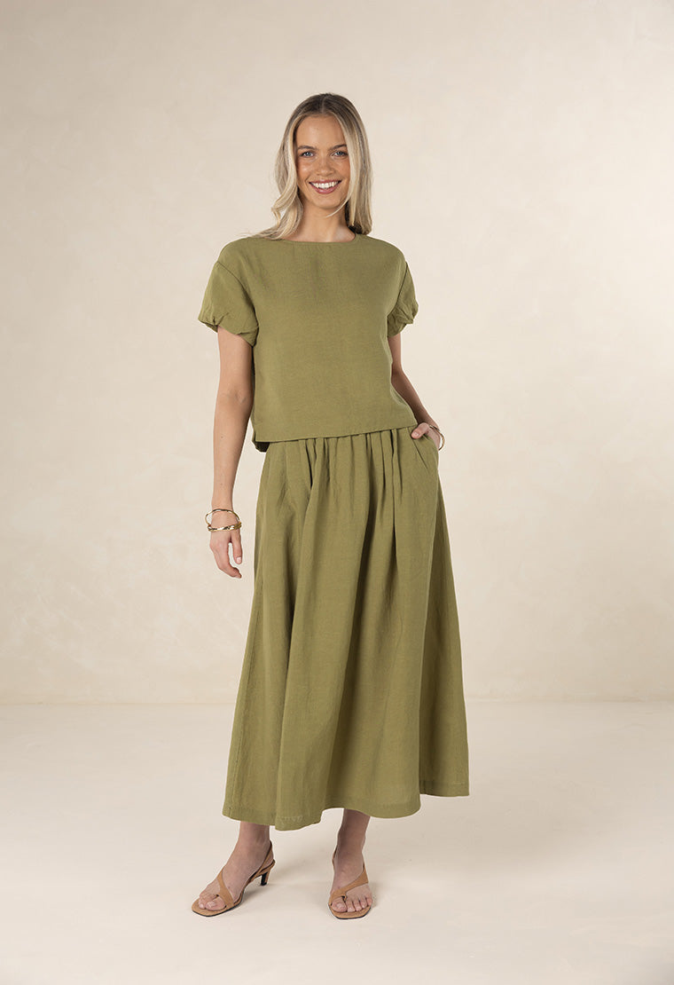 Woman wearing a green outfit on a beige background