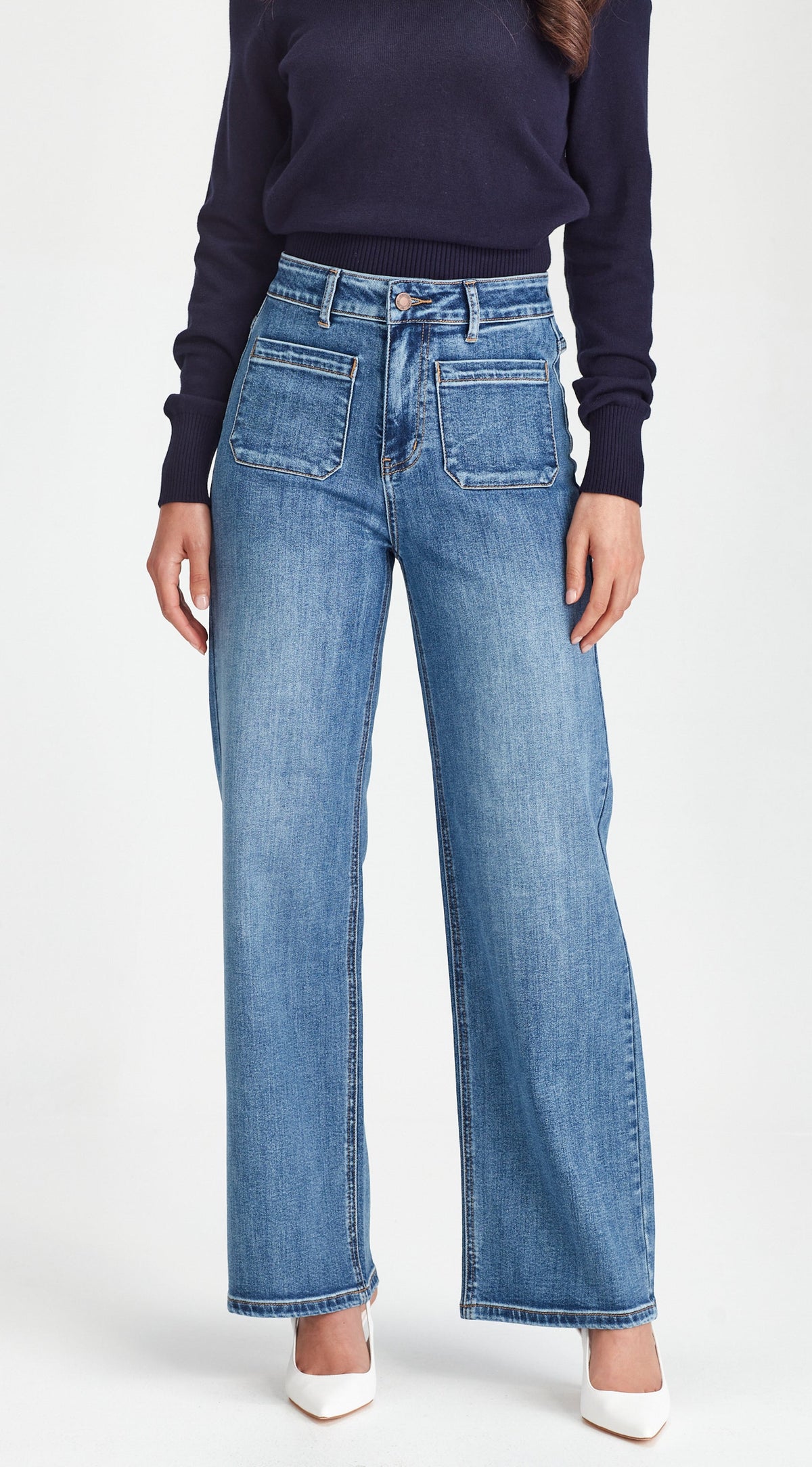 Person wearing blue jeans and a dark long-sleeve shirt on a white background
